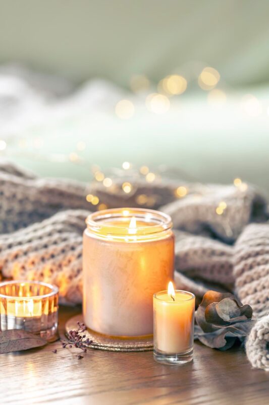 "luxury burning holiday candle with knitted scarf on wooden table"